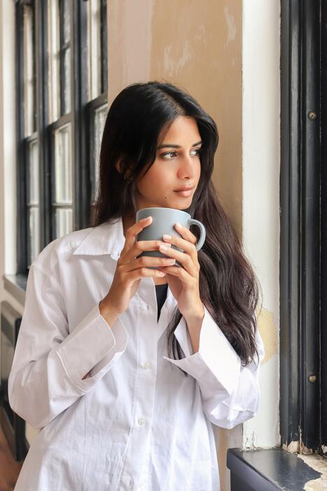 A girl in white shirt having a grey coffee